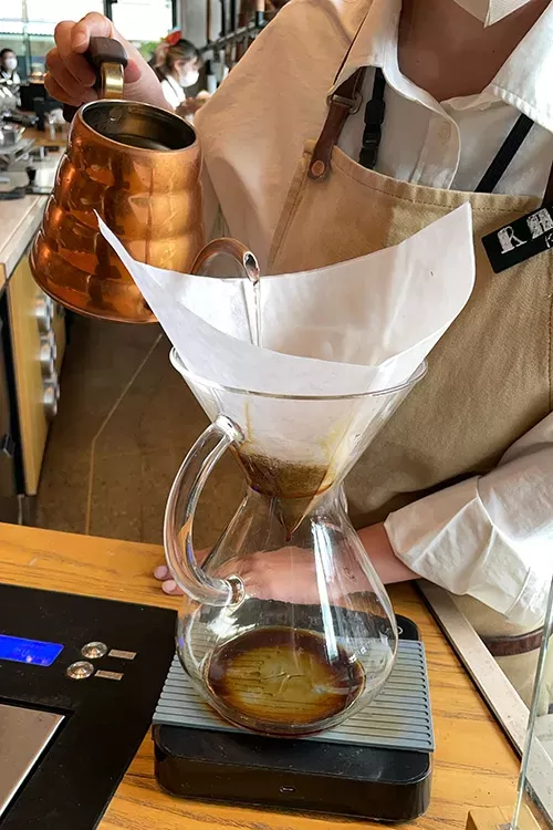 写真：バリスタさんがケメックスでコーヒーを抽出しているところ